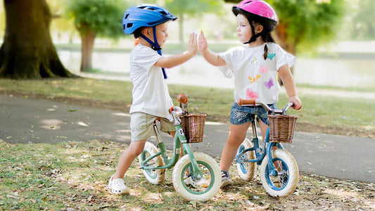 two children playing on bikes wearing pink and blue helmet